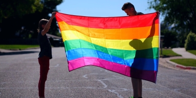Two people holding up a pride flag